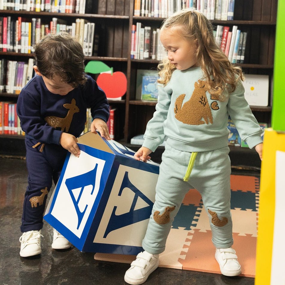 Two children playing with a blue and white block in a library setting.